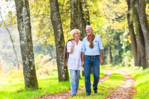 Senior woman and man, a couple, embracing each other having walk in the fall forest