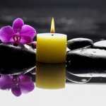burning yellow candles with pink orchid on blacks