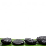 Spa stones on green leaf, isolated background